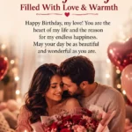 A man kisses his smiling wife on the forehead as she holds a bouquet and sits beside a birthday cake, surrounded by romantic decorations and warm lighting. Text overlay offers birthday wishes for a wife.